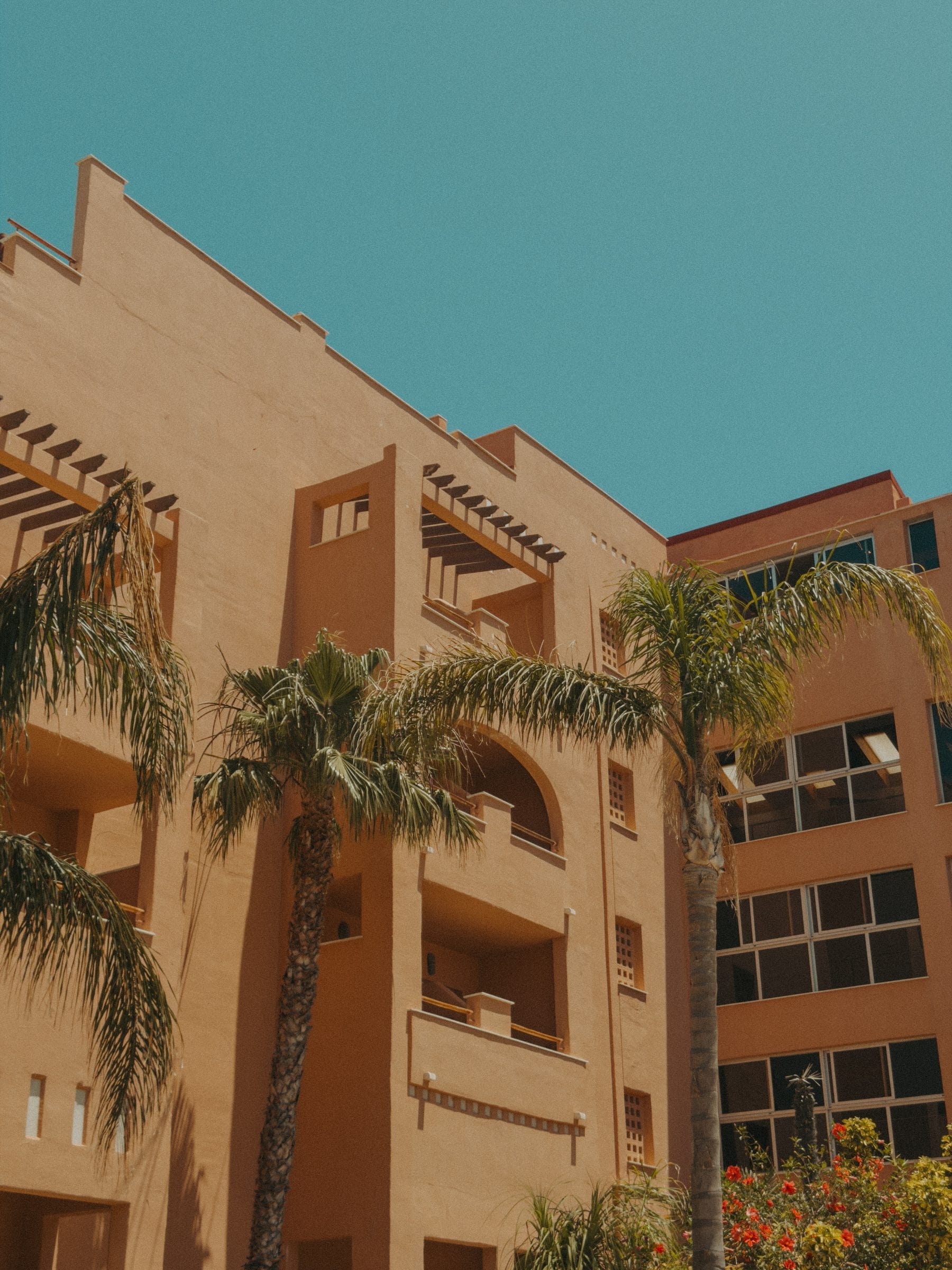 The terracotta facade of Hotel Tarifa Lances with palm trees against a blue sky