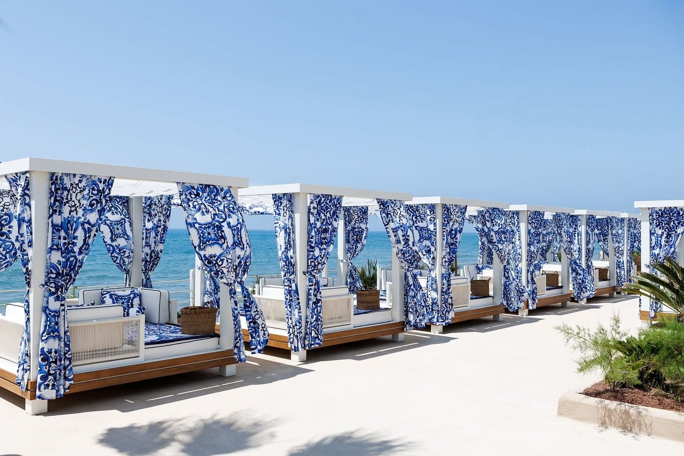 White cabanas draped in blue and white maiolica print facing the sea at La Cabane, Marbella